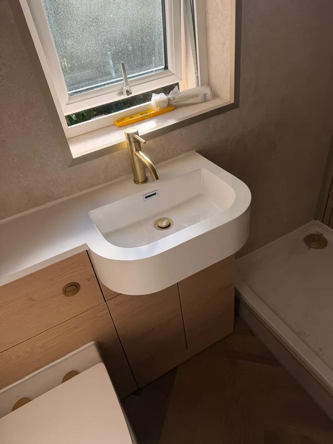 Brushed brass tap, curved basin and oak-effect vanity